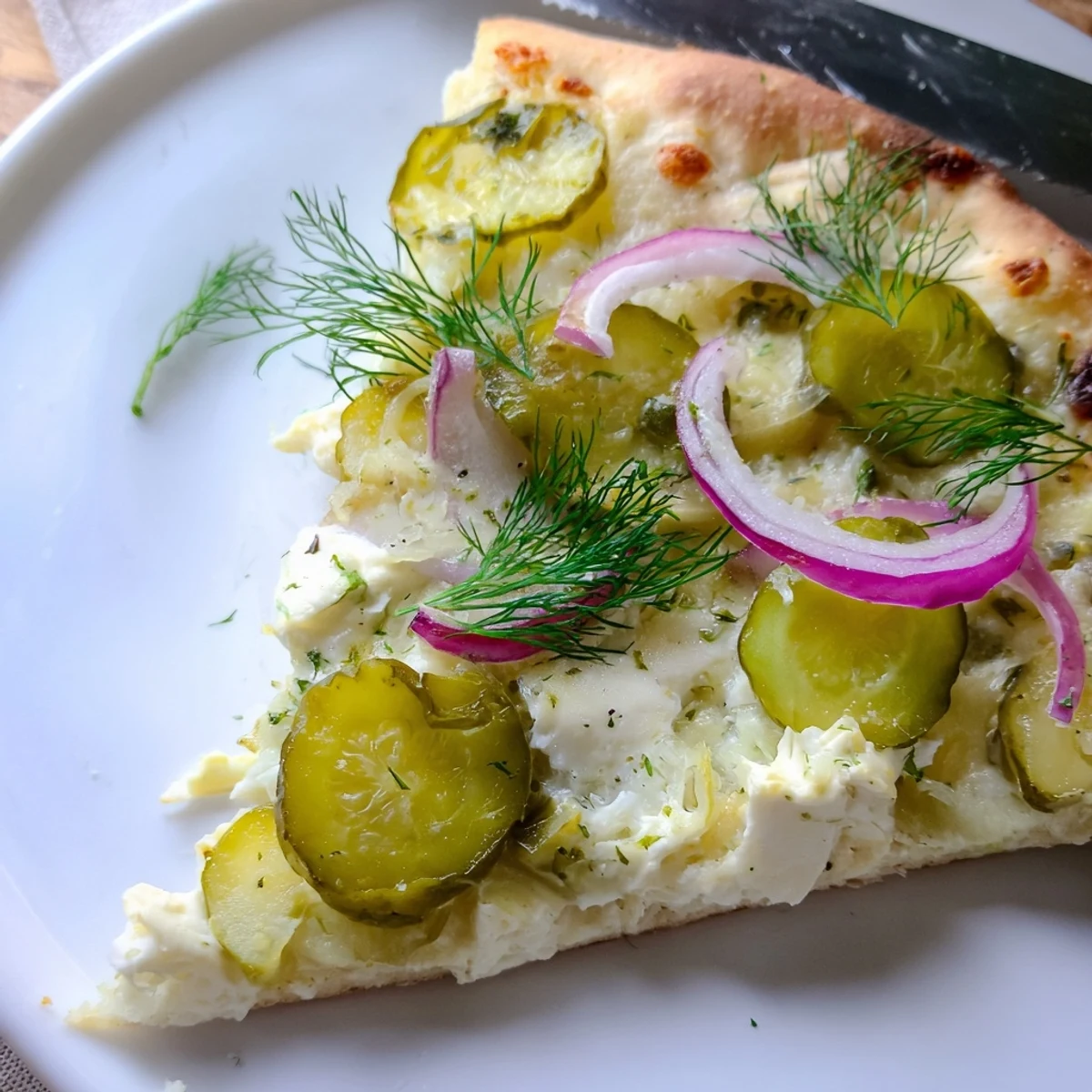 Golden-brown Pickle Pizza featuring a rich crème fraîche sauce and melted mozzarella.