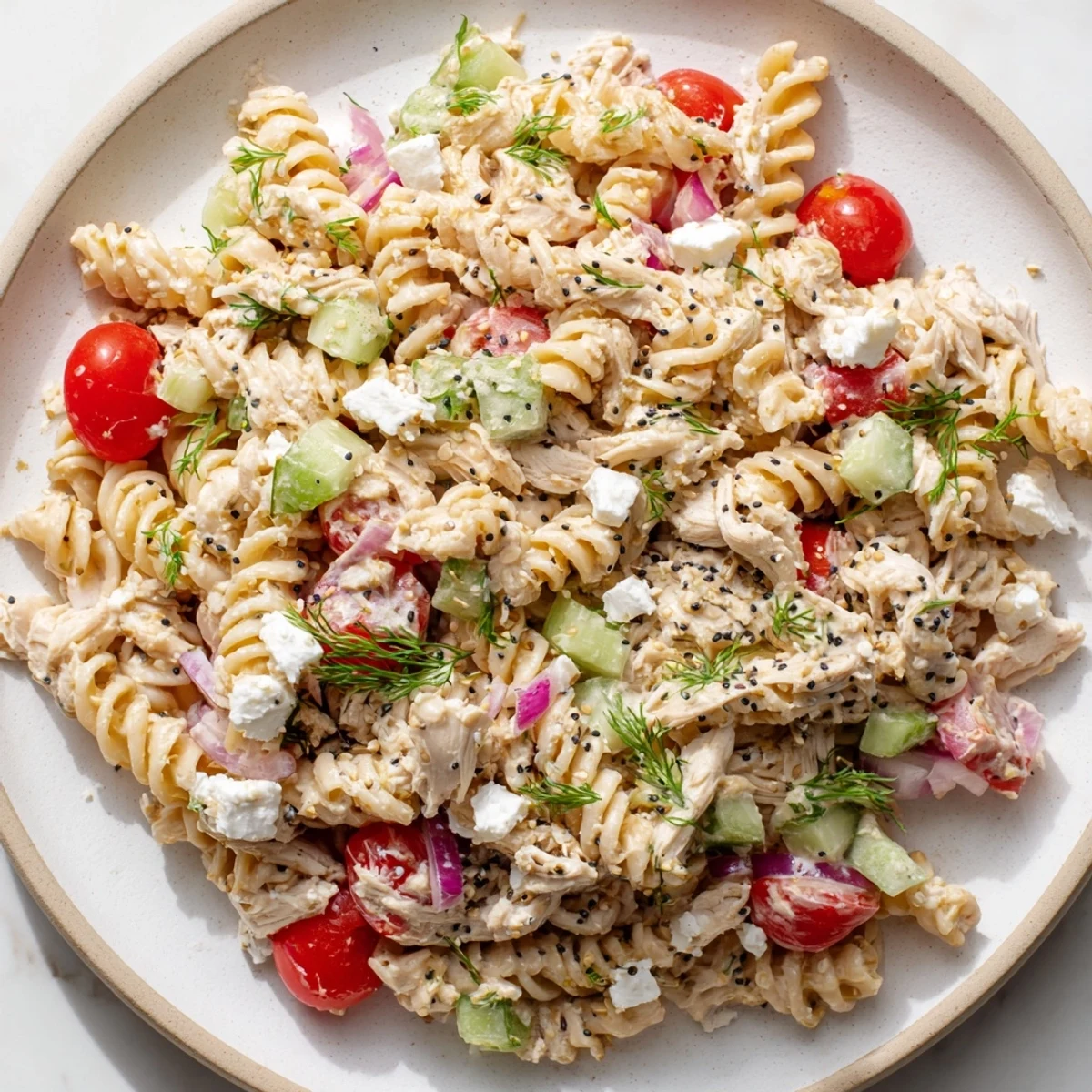 A close-up of Everything Bagel Chicken Pasta Salad, perfect for a picnic, with crunchy vegetables and creamy sauce.