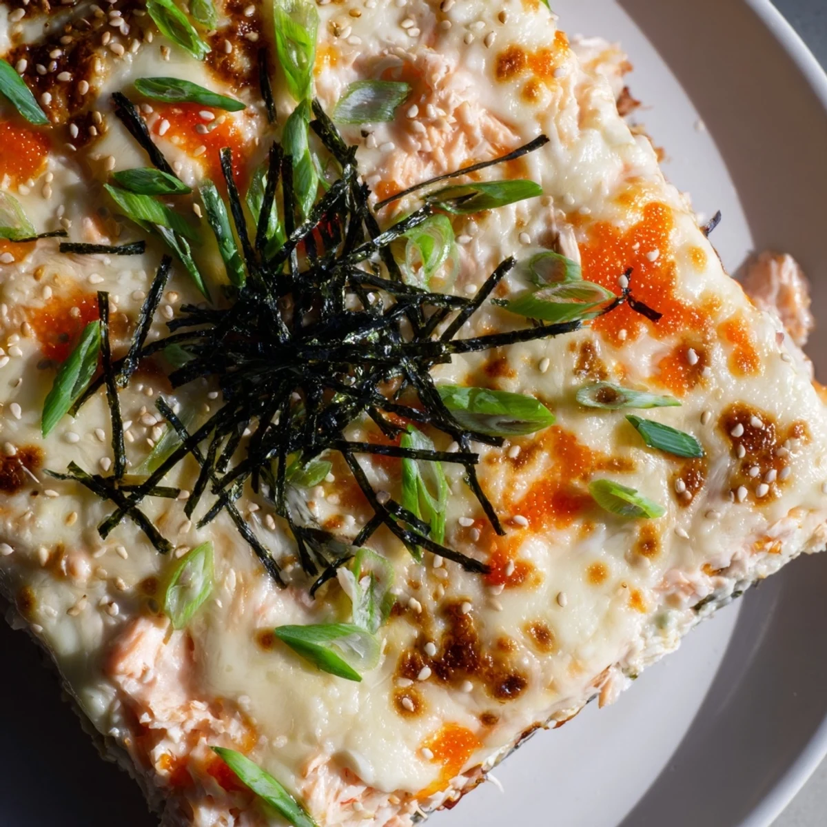 A bubbly, baked Creamy Salmon Sushi Bake, featuring flaky salmon and creamy sauce, perfect for serving.