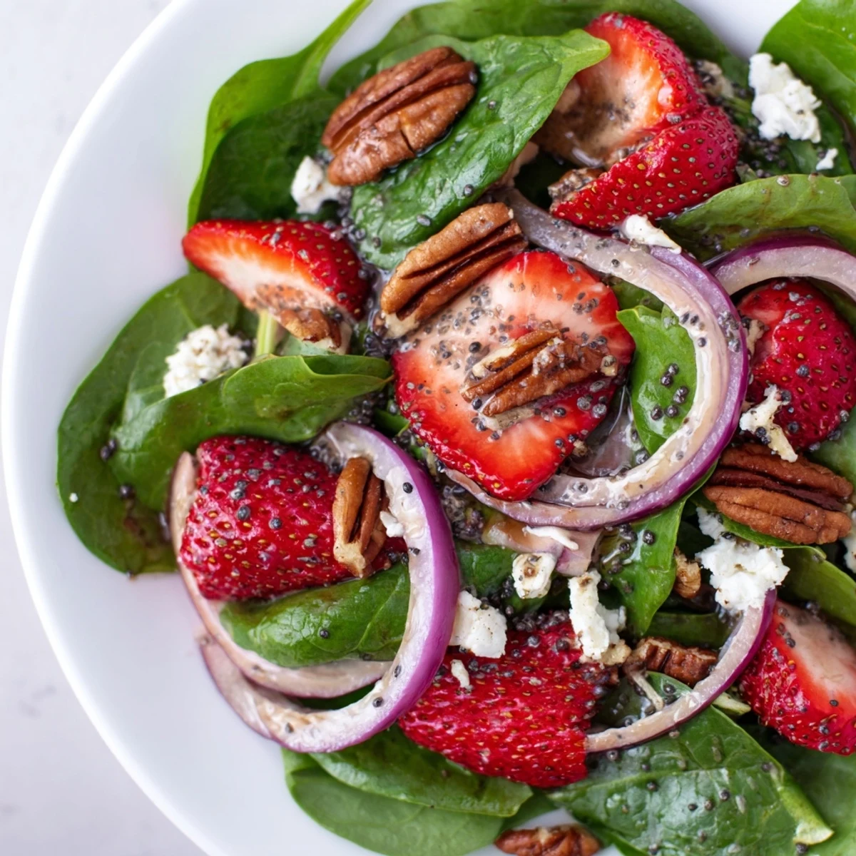 Fresh spinach strawberry salad bursting with color, topped with crunchy pecans ready to enjoy.