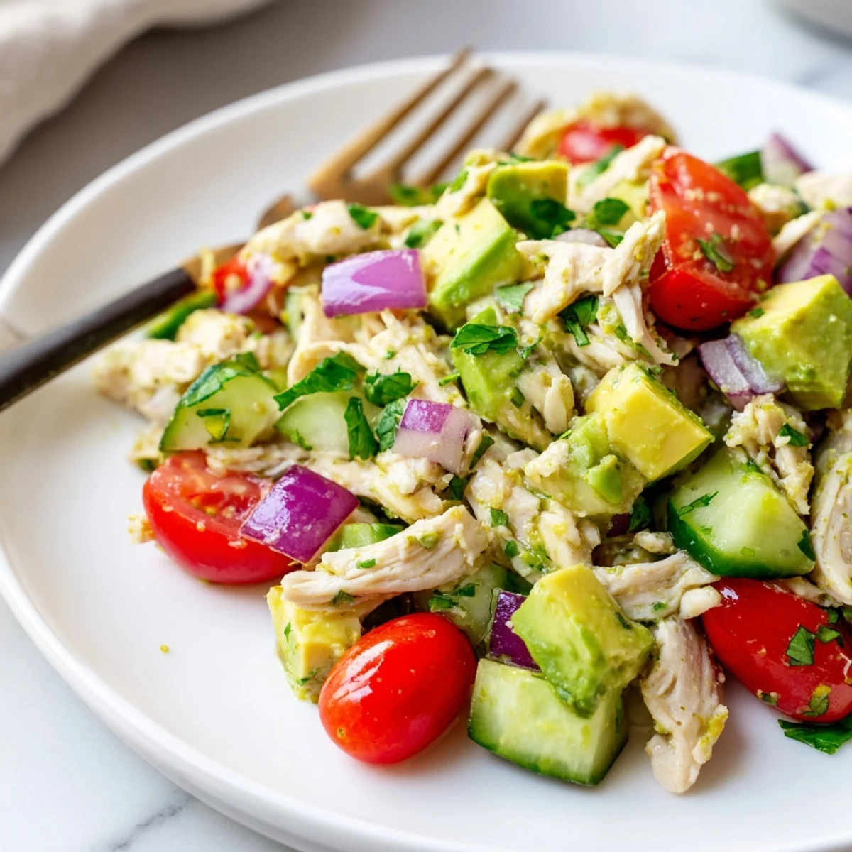 Creamy avocado chicken salad with tender shredded chicken, cherry tomatoes, and cucumber in a bright lime dressing.