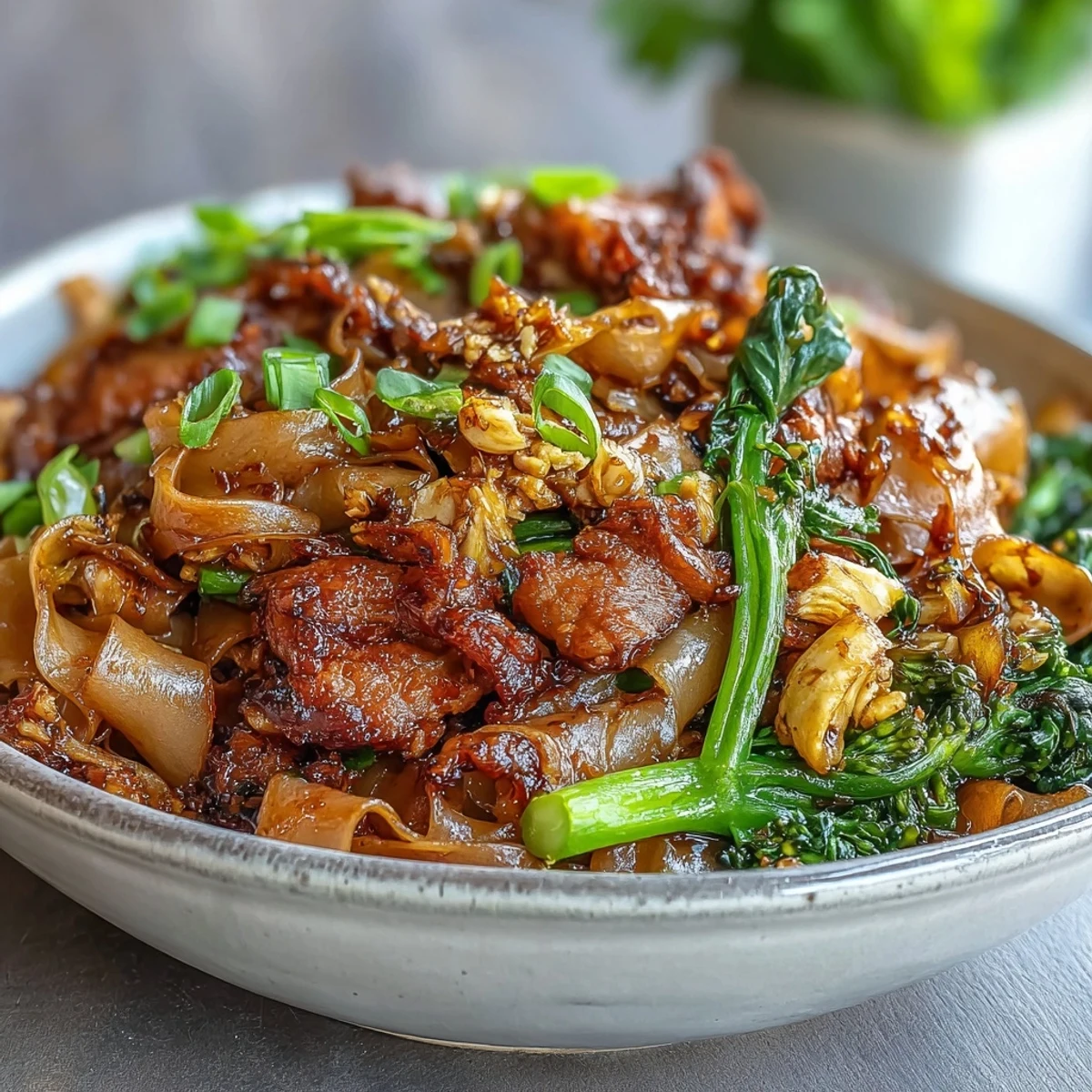 Steaming Authentic Thai Pad See Ew with tender chicken and Chinese broccoli on a dark plate.