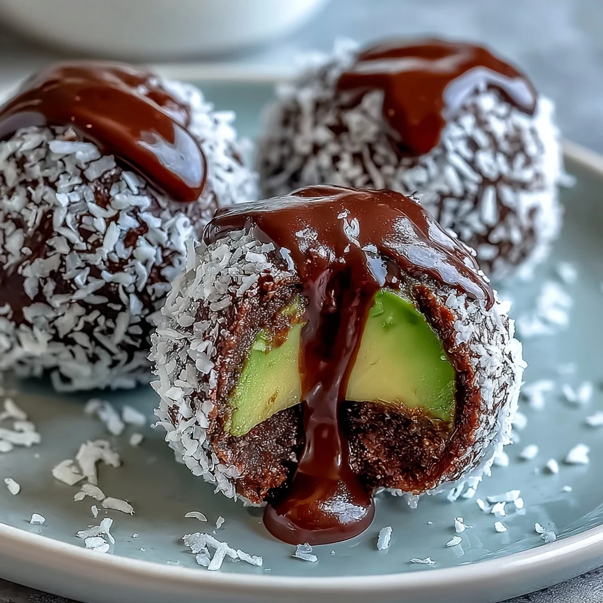 Freshly rolled Vegan Chocolate Avocado Truffles coated in shredded coconut on a plate.