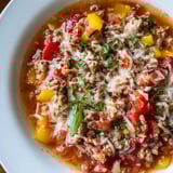 Hearty Pizza Soup with sausage and veggies, topped with gooey cheese, perfect for chilly evenings.