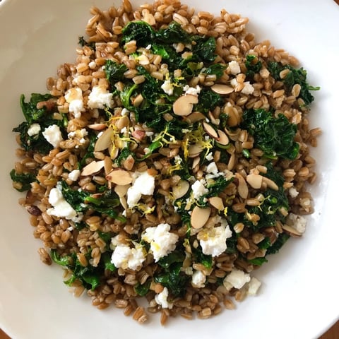 Warm farro and greens pilaf, speckled with bright herbs and toasted almonds, ready to serve.