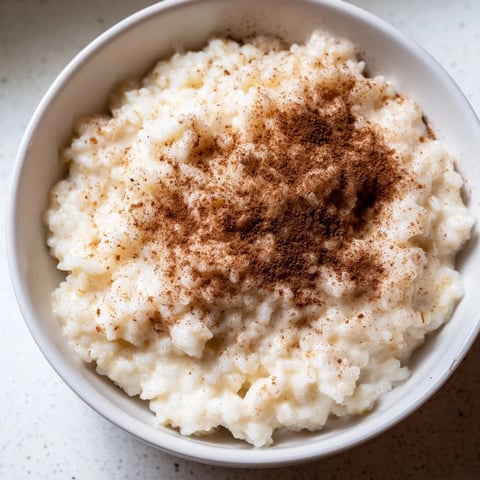 A warm bowl of creamy Rice Pudding with Leftover Rice, dusted with cinnamon, a comforting dessert.