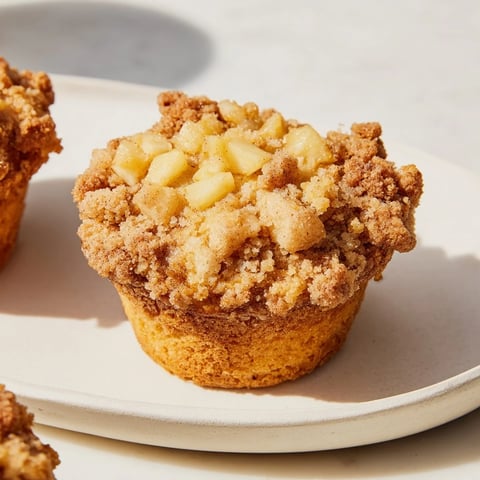 Golden-brown tasty apple muffins with a delicious, crunchy crumb topping, ready to eat.