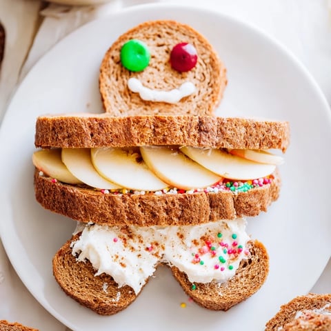 Gingerbread Man Sandwich cutouts, playfully decorated with fruit and smiling faces, ready to enjoy.