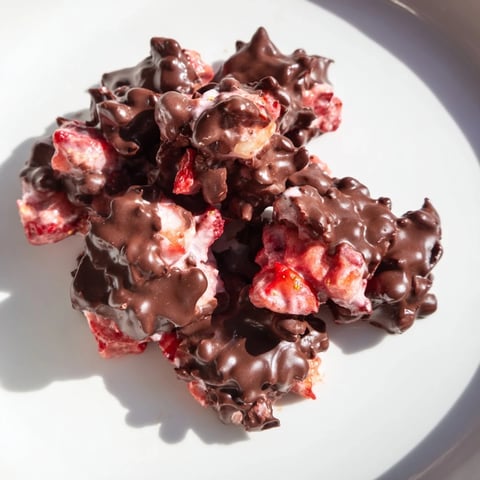 Frozen Strawberry Yogurt Clusters, gleaming with a dark chocolate shell, await a refreshing bite.