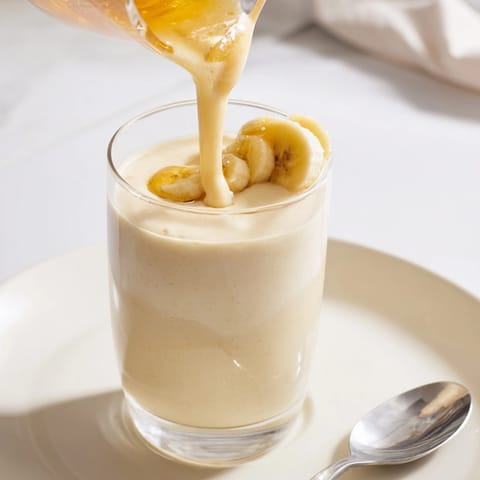 Close-up of a Healthy Banana Smoothie's thick, creamy texture, garnished with banana slices.