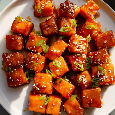 Golden-brown honey garlic salmon bites topped with green onions for a flavorful appetizer.  