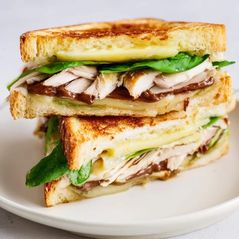 Delectable close-up of a Nutella grilled cheese with chicken, showing the bubbling brie and tender chicken.