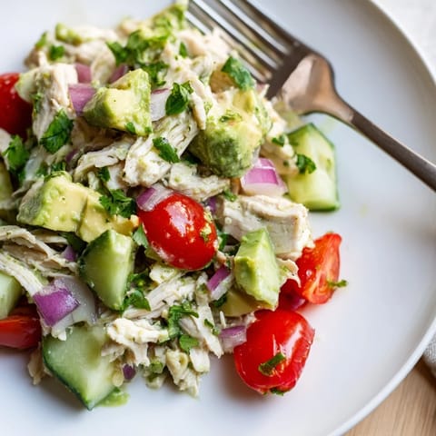 Freshly tossed avocado chicken salad on a white plate, served as a light, low-carb lunch for four.