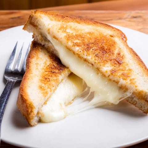 A close-up of the Mozzarella Stick Grilled Cheese oozing with stringy cheese beside marinara.
