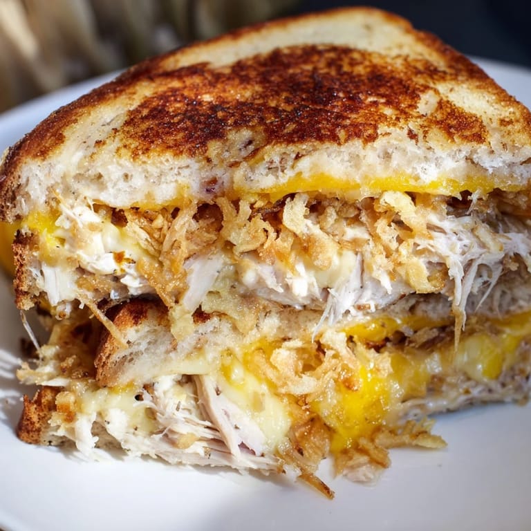 A close-up shot of a perfectly grilled Crispy Shallot Chicken Grilled Cheese, ready to be sliced and enjoyed.