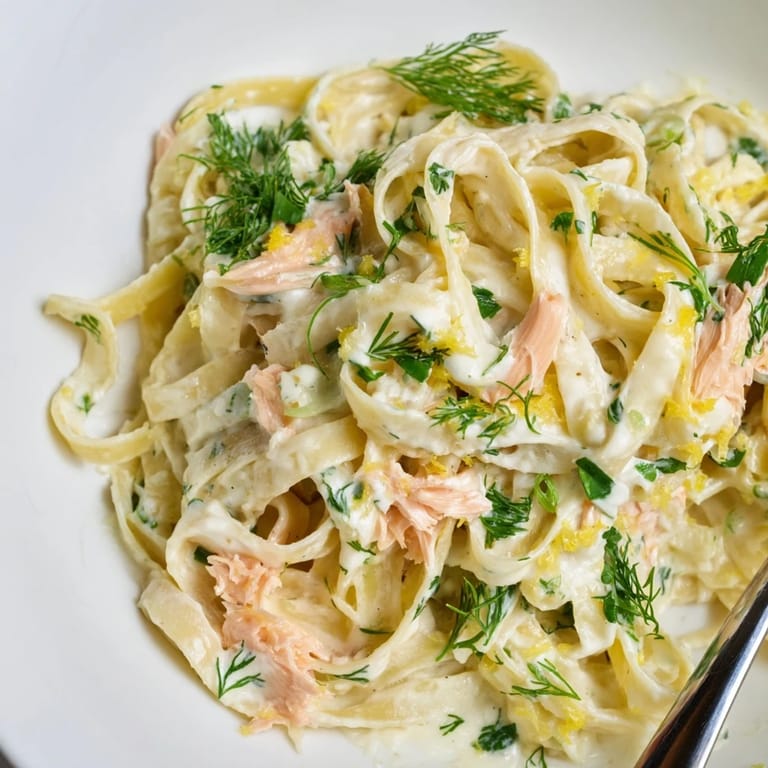 The Best Creamy Salmon Pasta served steaming in a skillet, fresh herbs and lemon zest sprinkled over a rich, creamy sauce.