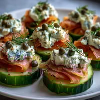 Bright Keto Smoked Salmon and Cream Cheese Cucumber Bites garnished with fresh dill and capers, served on a platter.