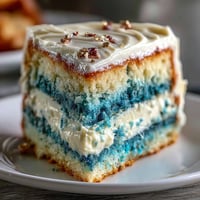 Graduation cake for boys with dark blue and gold ombre layers, topped with smooth vanilla buttercream and elegant edible gold leaf accents.