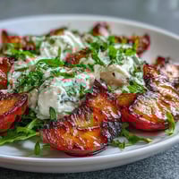 Grilled peach and burrata salad with honey, featuring sweet caramelized peaches and creamy cheese on a bed of arugula.